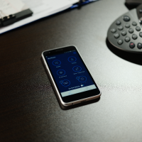 cell phone on table next to conference call receiver